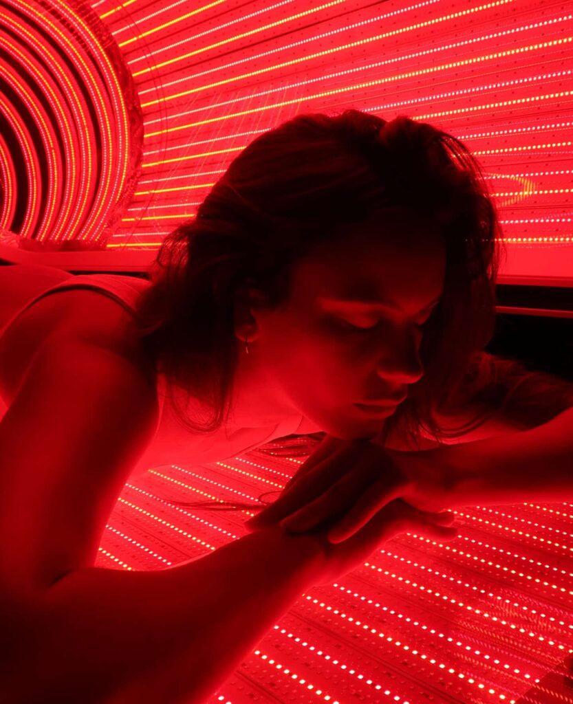 woman lying down in red light bed